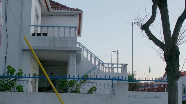 A white house by the street with a small blue railing.