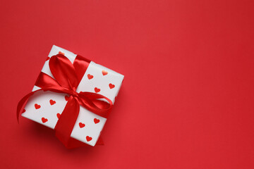 Beautiful gift box with red hearts on color background