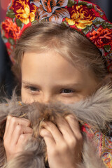 A blonde girl in a national Russian costume on the Maslenitsa holiday. A beautiful russian girl in a national costume made of a fur cape and kokoshnik. Close-up portrait