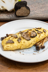 French omelette with mushrooms, fresh farmers eggs and black summer truffle mushroom in pieces for making truffle dishes with tasty aroma