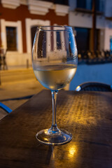 Glass of cold dry white wine served outdoor in cafe at night in historical Triana district, Sevilla, Spain, close up