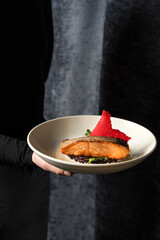 A piece of baked red fish on vegetables in a white bowl