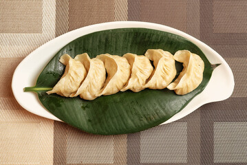 Freshly steamed dim sums or momos served on a leaf,  perfect for food blogs, Asian cuisine menus, restaurant ads or culinary magazines.