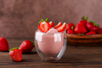 Vegan homemade strawberry tofu soy yogurt in a glass on a wooden table. Lactose and sugar free. Selective focus.