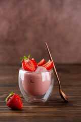 Whipped strawberry tofu and mousse dessert in a glass with spoon. Vegan food. Lactose and sugar free. Selective focus. Vertical orientation.