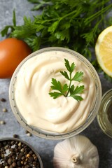 Bowl with mayonnaise and ingredients for cooking on gray background