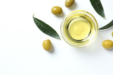 Bowl of fresh olive oil and olives with leaves on white background