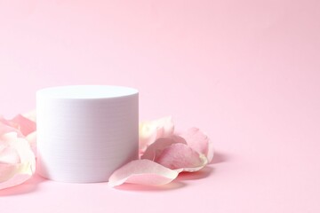 Pink rose petals with podium on a color background