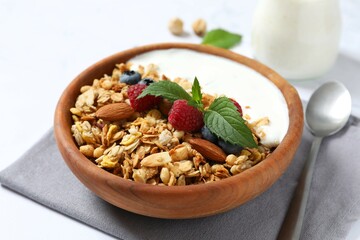 Delicious granola with berries and yogurt on a light background
