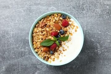 Delicious granola with berries and yogurt on a gray background