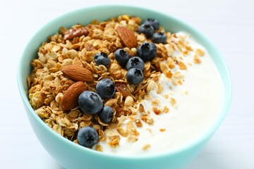 Delicious granola with berries and yogurt on a light background