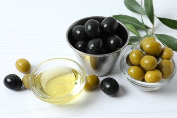 Bowl of fresh olive oil and olives with leaves on the table