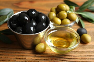 Bowl of fresh olive oil and olives with leaves on the table
