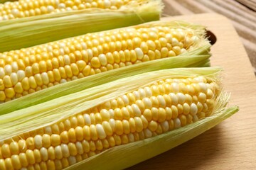 Fresh corn on cobs on wooden background, top view