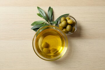 Bowl of fresh olive oil and olives with leaves on the table