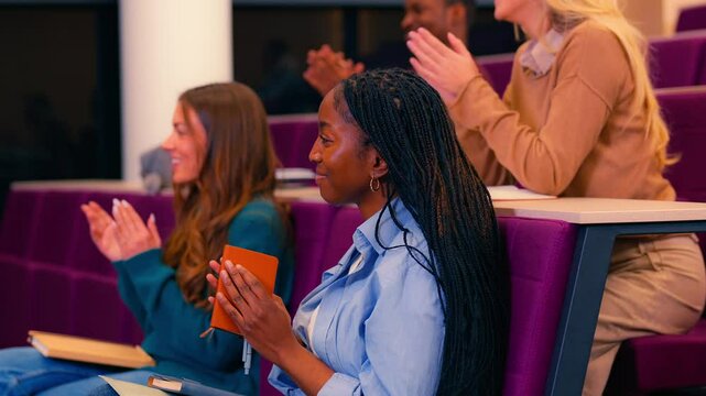 University students applauding professor with enthusiasm at lecture's conclusion, showing appreciation for inspiring academic moment in modern lecture hall through slow motion gesture