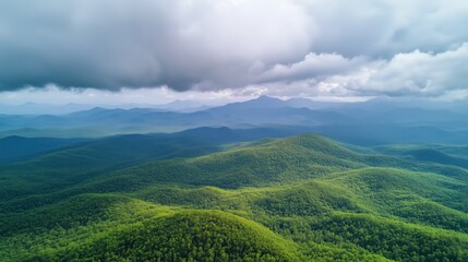 Fototapeta premium The verdant mountains stretch endlessly, their vibrant hues contrasting beautifully with the soft, textured clouds above, offering a serene and awe-inspiring view.
