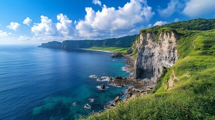 Coastal cliffs with lush greenery meeting crystal-clear ocean under a bright, cloud-filled blue sky