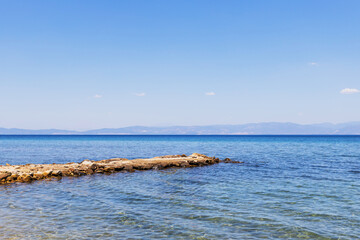 Tranquil scene of a stone pier extending into the calm, blue waters of the sea, summer vacation.