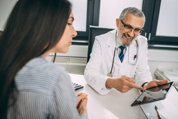 Fototapeta premium Every patient should have a clear understanding of their diagnostic. Shot of a handsome doctor going over some paperwork with a female young patient in a clinic.