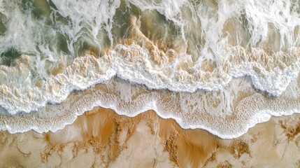 Aerial view of crashing ocean waves on sandy beach with foamy white surf and golden sand