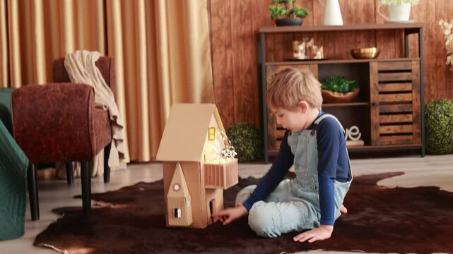 Child, cute boy, playing with toys in a playroom, teddy bear and little ducks with a paper house