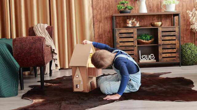 Child, cute boy, playing with toys in a playroom, teddy bear and little ducks with a paper house