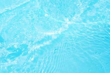 Blue water with ripples on the surface. Defocus blurred transparent blue colored clear calm water surface texture with splashes and bubbles. Water waves with shining pattern texture background.