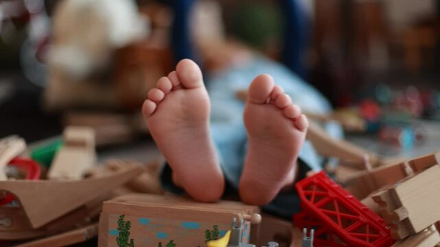 Child, cute boy, playing with toys in a playroom, focus on his feet