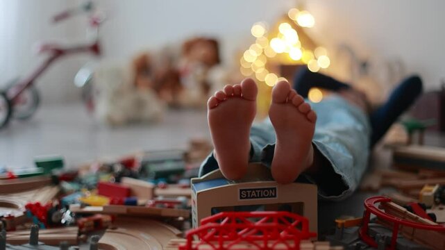 Child, cute boy, playing with toys in a playroom, focus on his feet