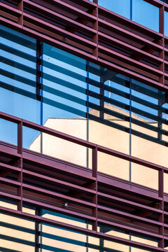 This image showcases a contemporary architectural facade, highlighting the interplay between glass surfaces and linear metal elements, creating an appealing visual effect.