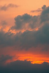 Obraz premium Fiery Sunset Hues: A breathtaking sunset paints the sky with vibrant oranges and deep reds, contrasted by dramatic dark clouds. The intense colors create a captivating scene of natural beauty. 