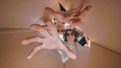 High school students enjoying summer break, playfully reaching out from inside a cardboard box...