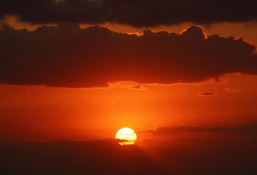 Orange sunset with dark clouds and sun rays