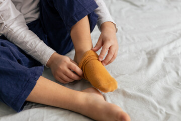 Child removing yellow socks on bed. Getting ready for bedtime