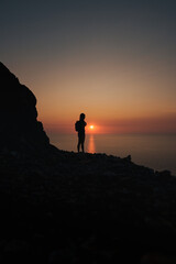 Fototapeta premium A hiker silhouetted against a glowing sunset over the Mediterranean in Mallorca.