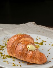 Fresh croissant with pistachio cream on a plate.