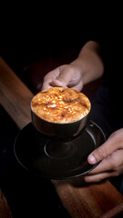 Coffee Creme Brulee Latte with black tea cup and cinematic light with hands serving