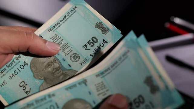Sion, Maharashtra, India-June 5th-2024-Close static shot of counting Indian 50 rupee notes with naked hands.