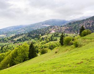 countryside mountain landscape in spring. cloudy weather forecast in may. field and forest on the...