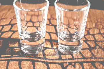 Tequila shot glass. Two empty shot glasses on wooden table. Alcohol equipment. Selective focus.	
