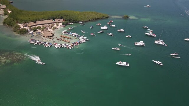 Cholon Island aerial video, tilting down moving towards the boats and tiki huts. Shot this aerial video mid-day at the busiest time while everyone is partying and yachts are surrounding the island.