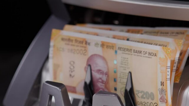 Close shot of Indian two hundred rupee notes coming out of the counting machine.