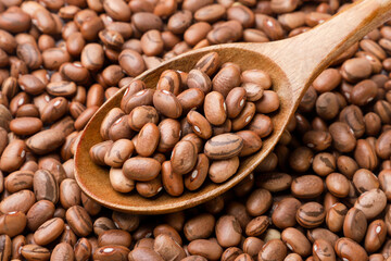 Brown beans in a wooden spoon. Background