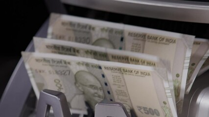 Close  shot of Indian five hundred rupee notes coming out of the counting machine.