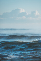 Ocean Waves Crashing Under a Blue Sky with Puffy Clouds