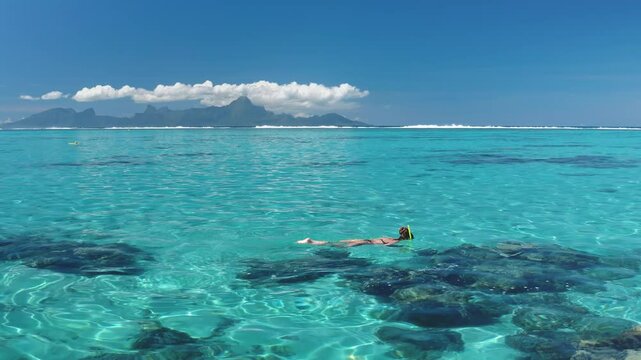 Snorkeling in clear turquoise waters near a tropical island. A woman immerses in the beauty of the underwater world. Offering an unforgettable experience