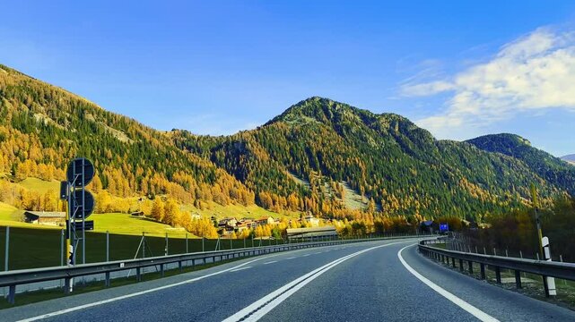 Car Point of View on Mountain Road with Trees in the Swiss Alps in Mountain Valley in a Sunny Autumn Day with Blue Sky in Sufers, Viamala, Grisons, Switzerland.