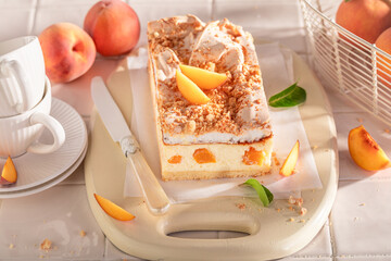 Tasty peach cheesecake served on bright kitchen.