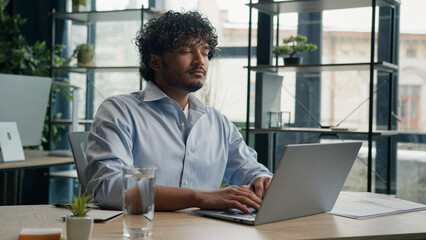 Tired Arabian Indian man businessman working on laptop relaxed male worker peaceful guy dream...